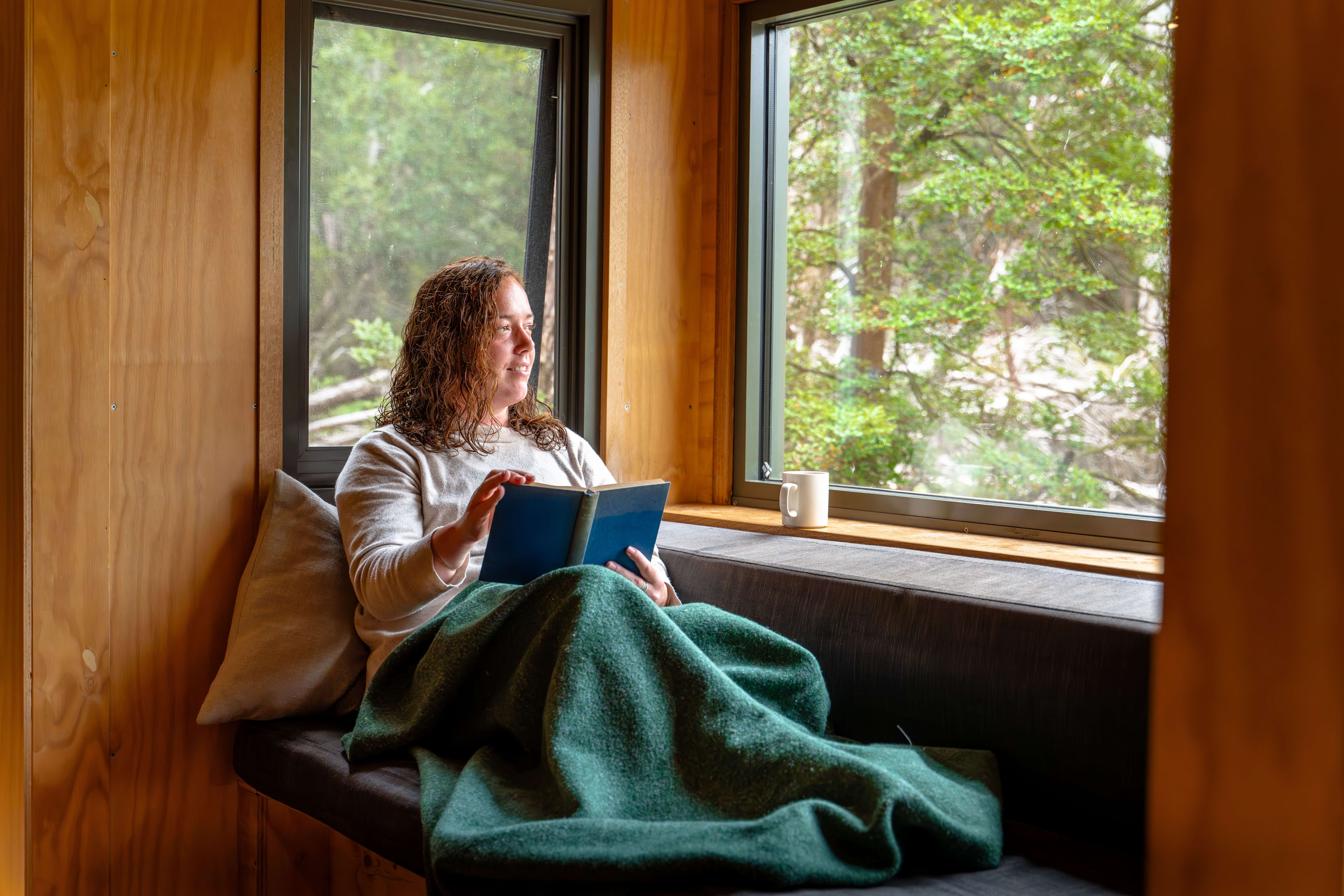 Woman peacefully reading in a cozy window nook, depicting calm and no social pressure